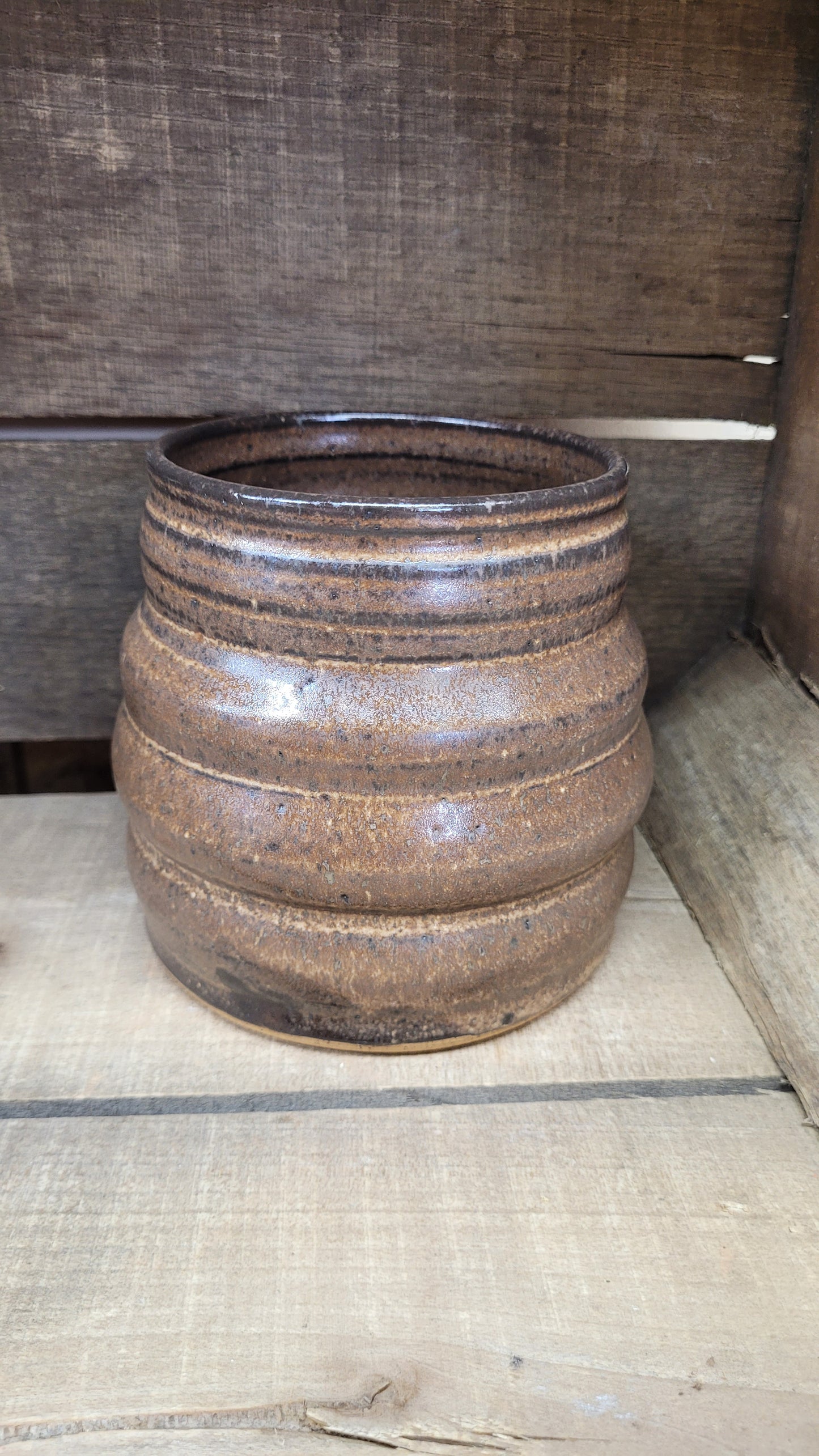 Ceramic vase with brown glaze on a wooden surface with tape measure