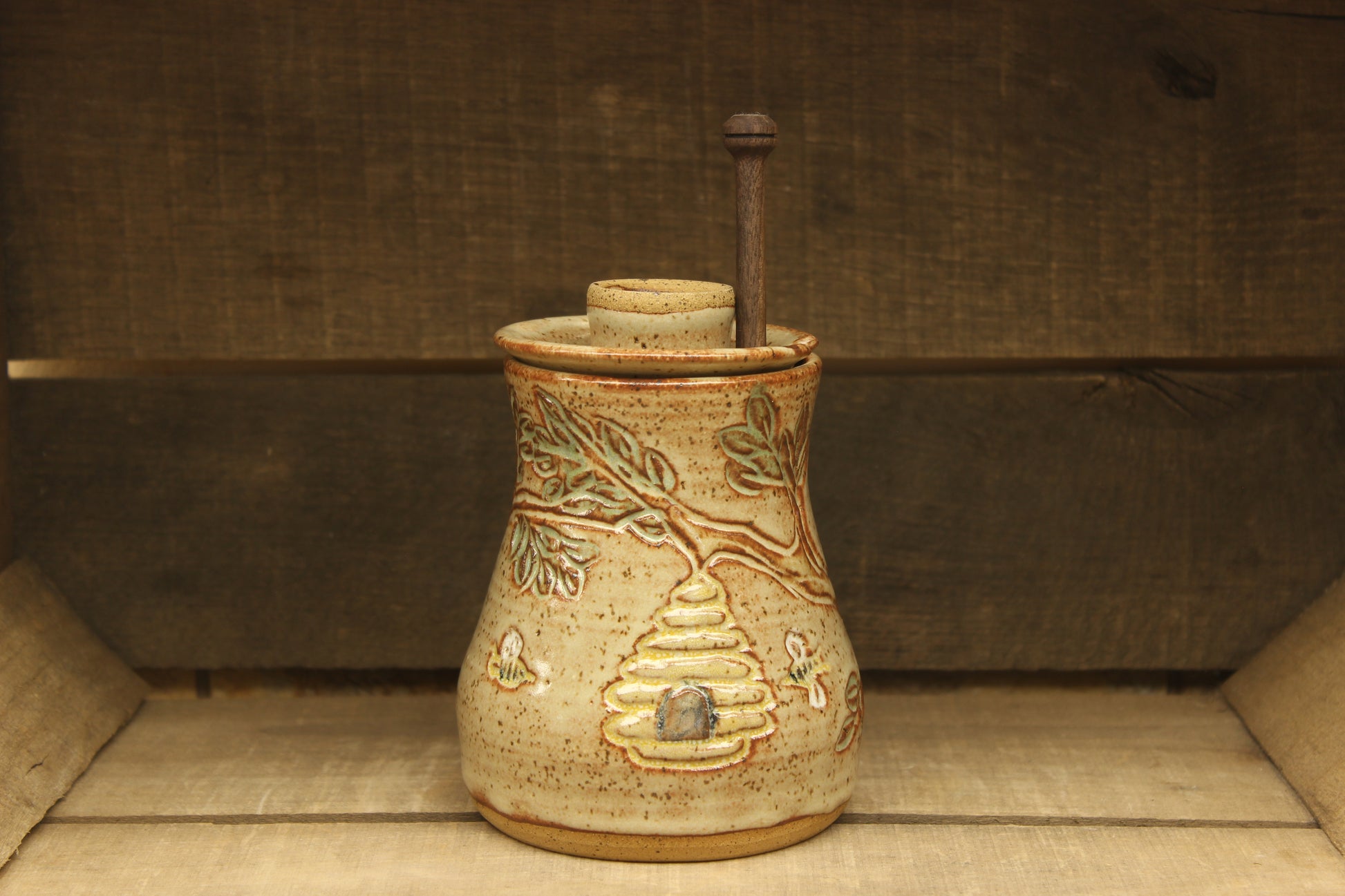 Ceramic honey pot with beehive and bees with a wood honey dipper