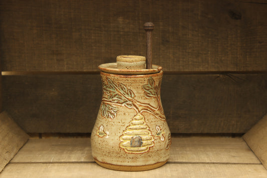 Ceramic honey pot with beehive and bees with a wood honey dipper