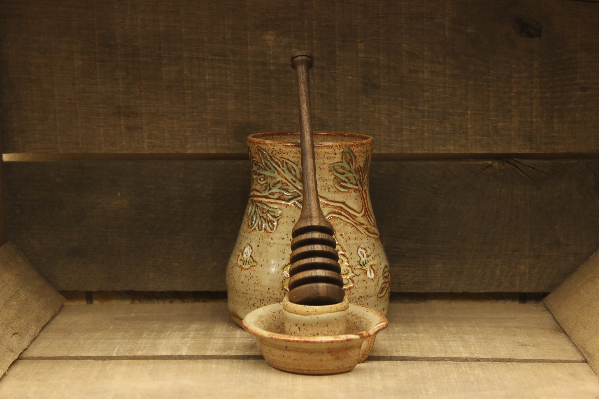 Ceramic honey pot with beehive and bees with a wood honey dipper