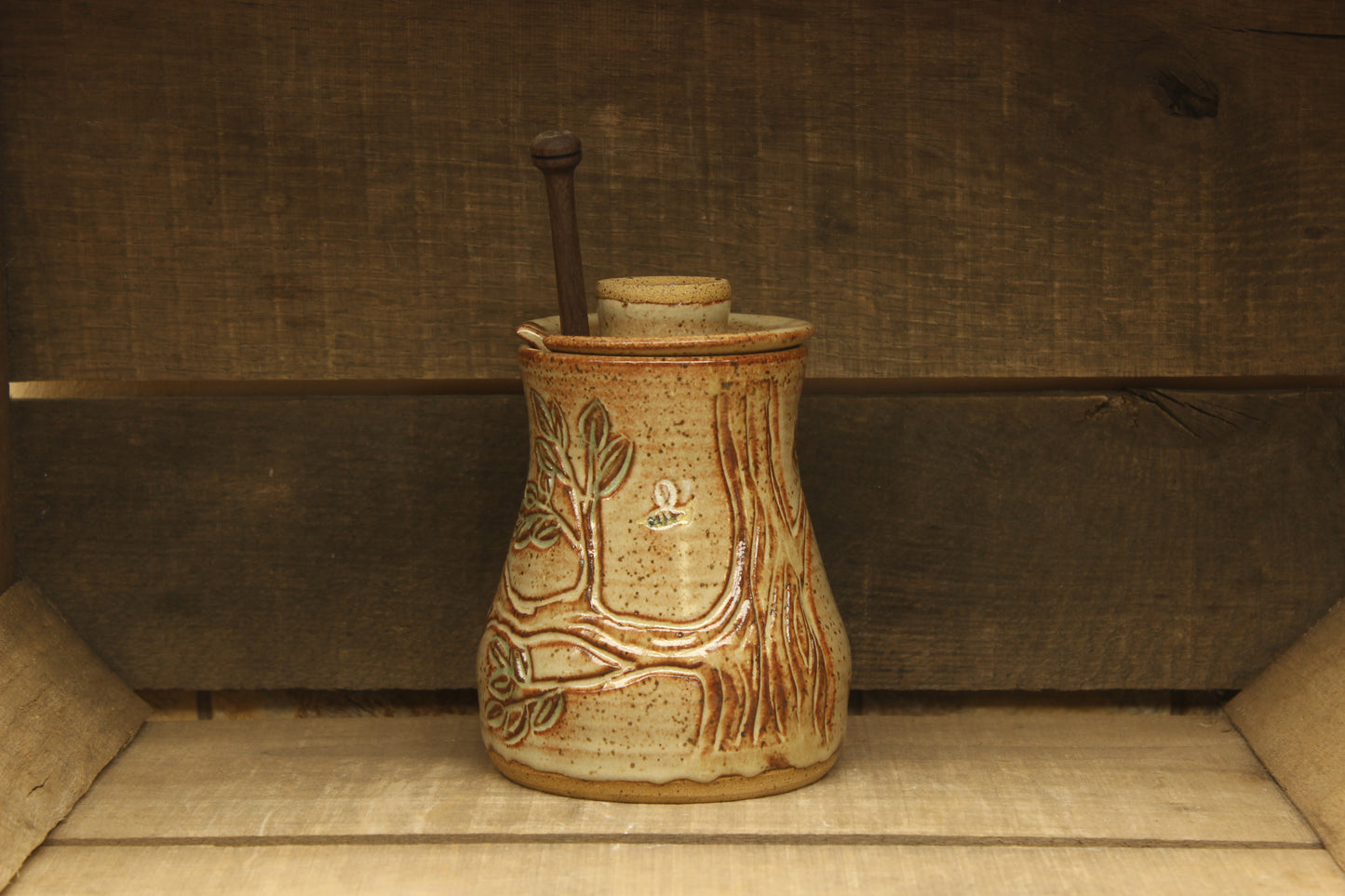 Ceramic honey pot with beehive and bees with a wood honey dipper