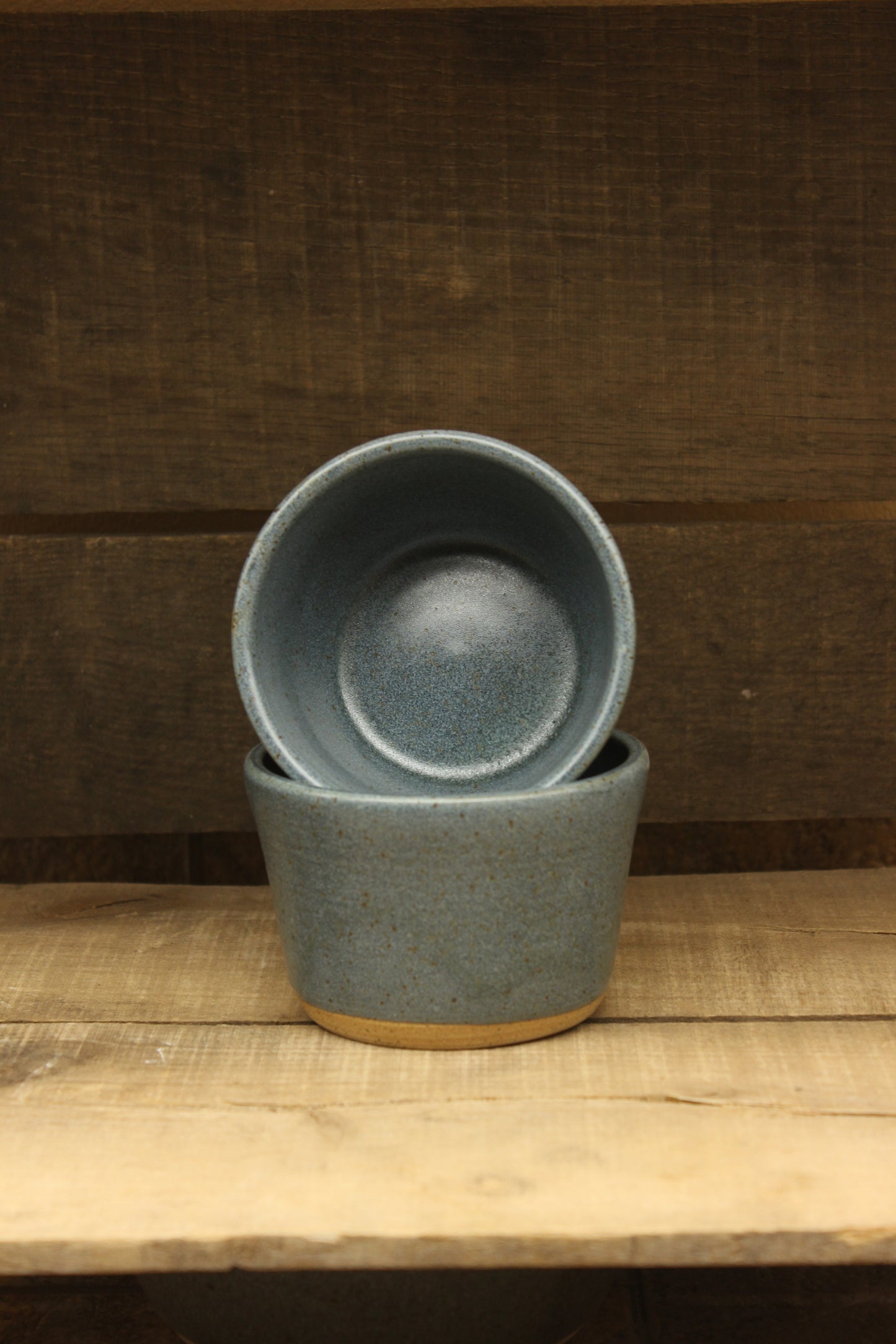 Two gray ceramic cups on a wooden surface