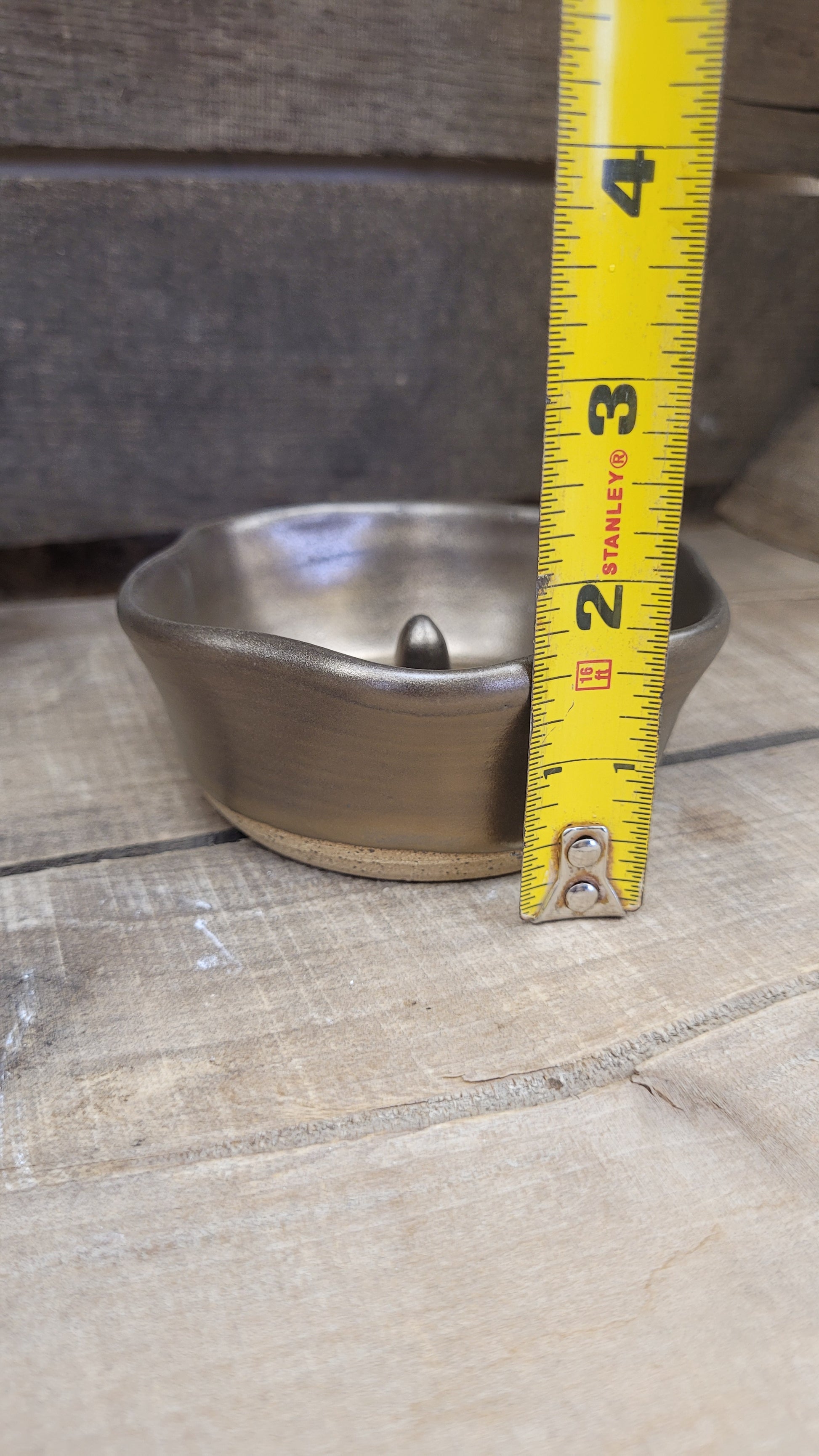 Gold ring dish on wood surface with tape measure