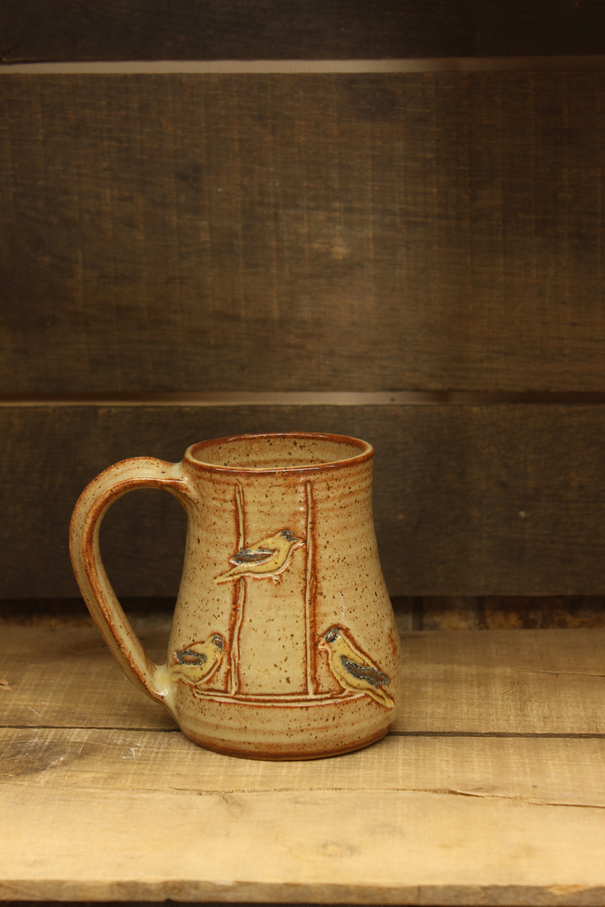 wheelthrown ceramic mug with goldfinches at feeder