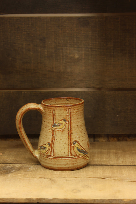 wheelthrown ceramic mug with goldfinches at feeder