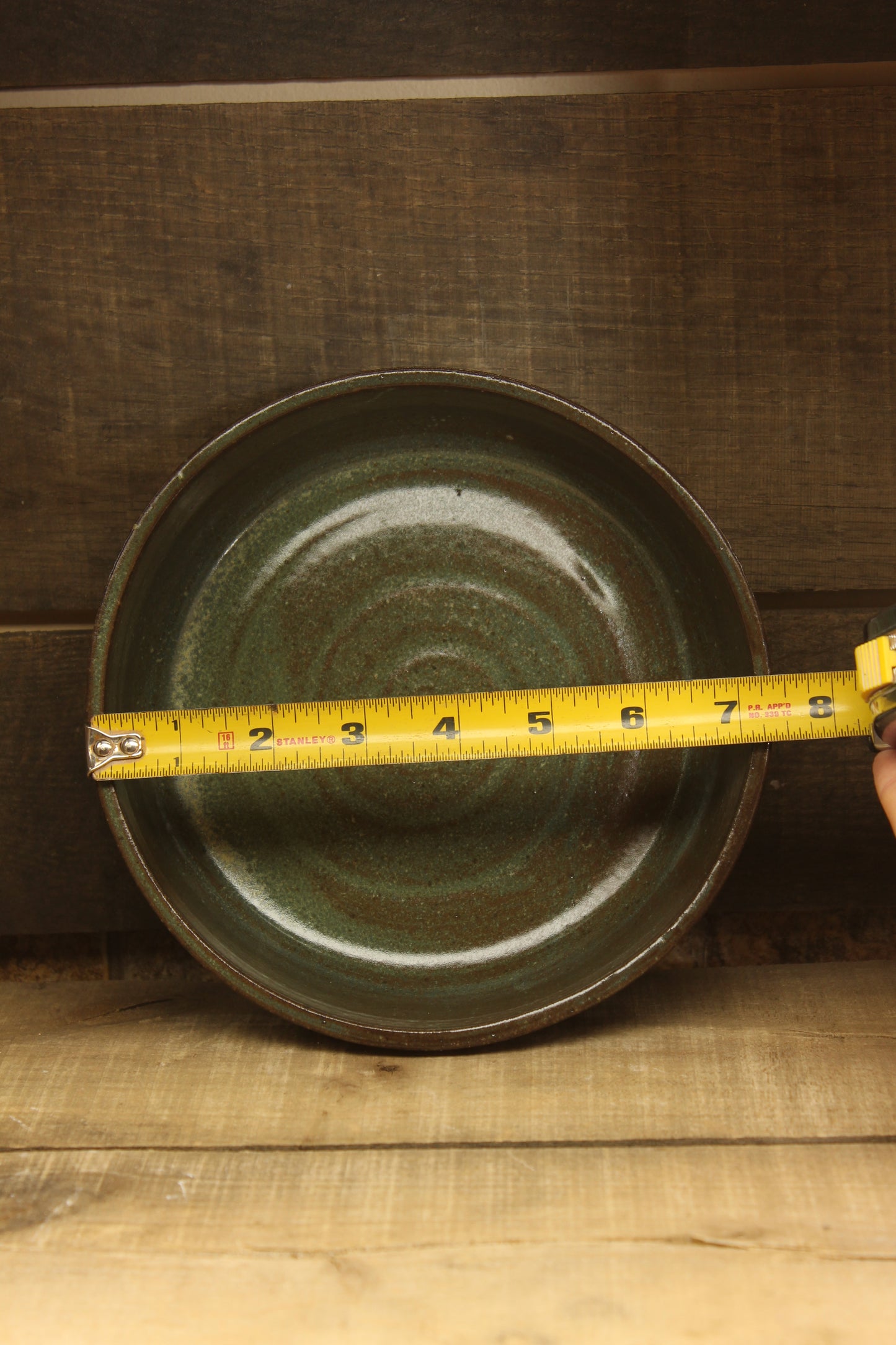 Green ceramic plate with a measuring tape on a wooden surface