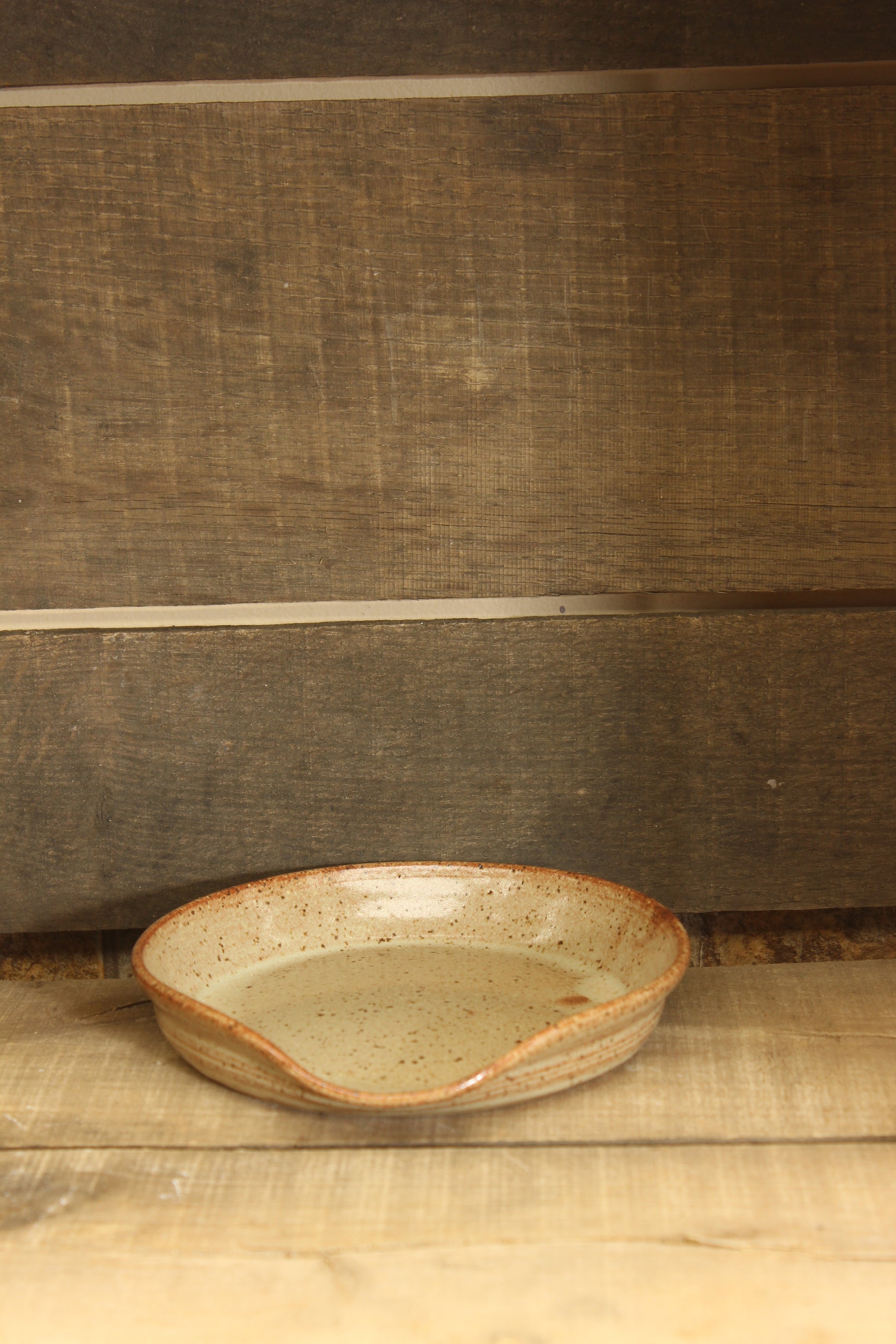 Ceramic tan spoon rest on a wooden surface