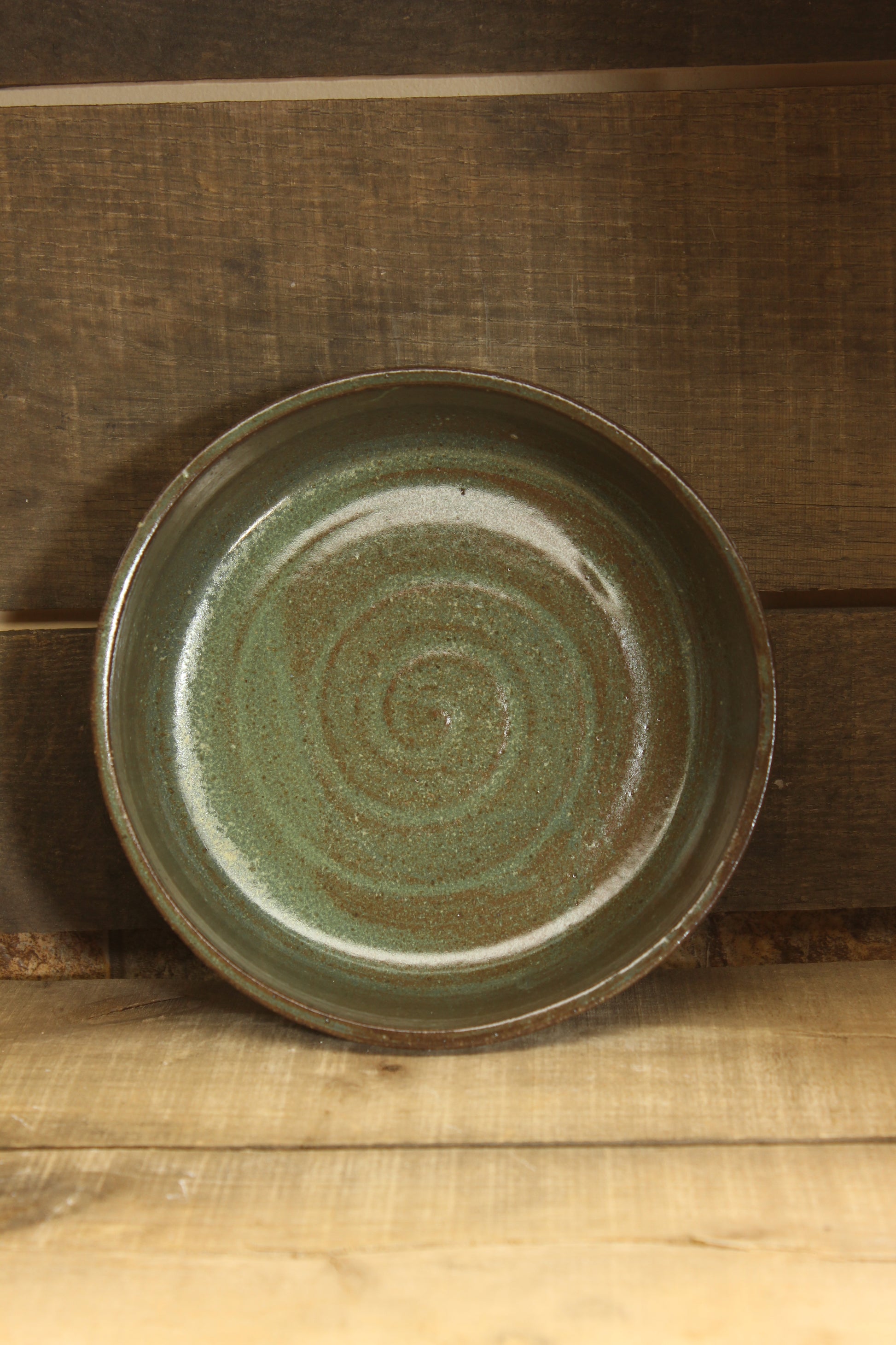 Green ceramic plate with a spiral pattern on a wooden surface