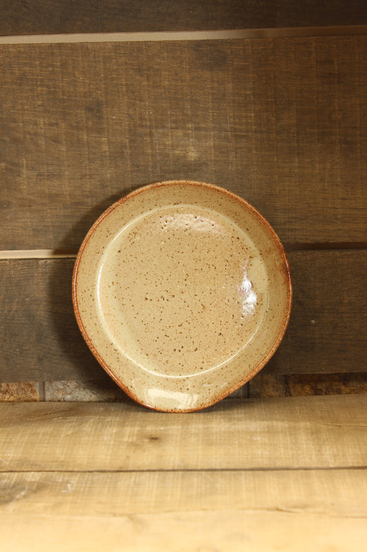 Ceramic plate with brown rim on a wooden surface