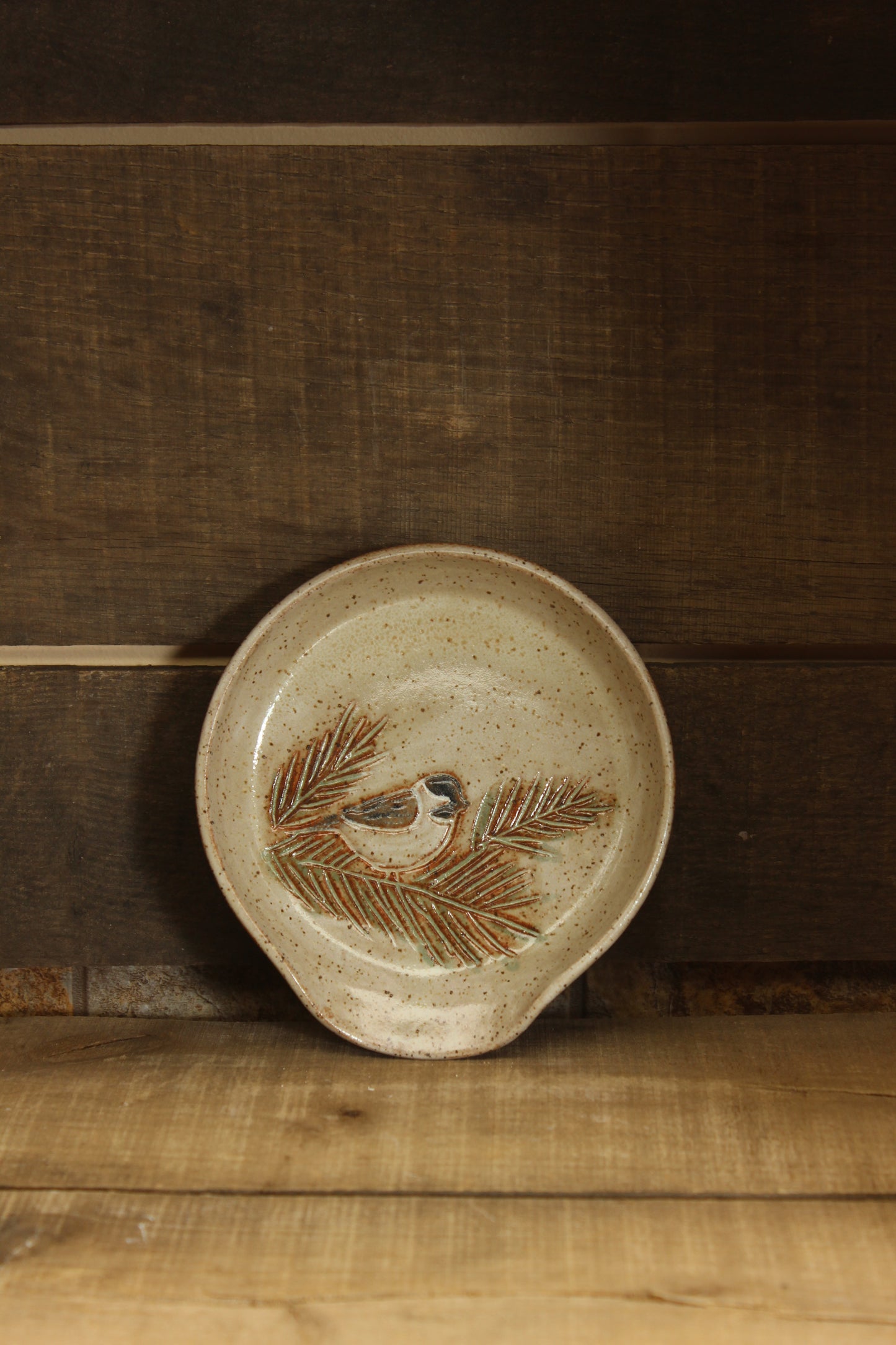Ceramic dish with chickadee and pine branch design on a wooden surface