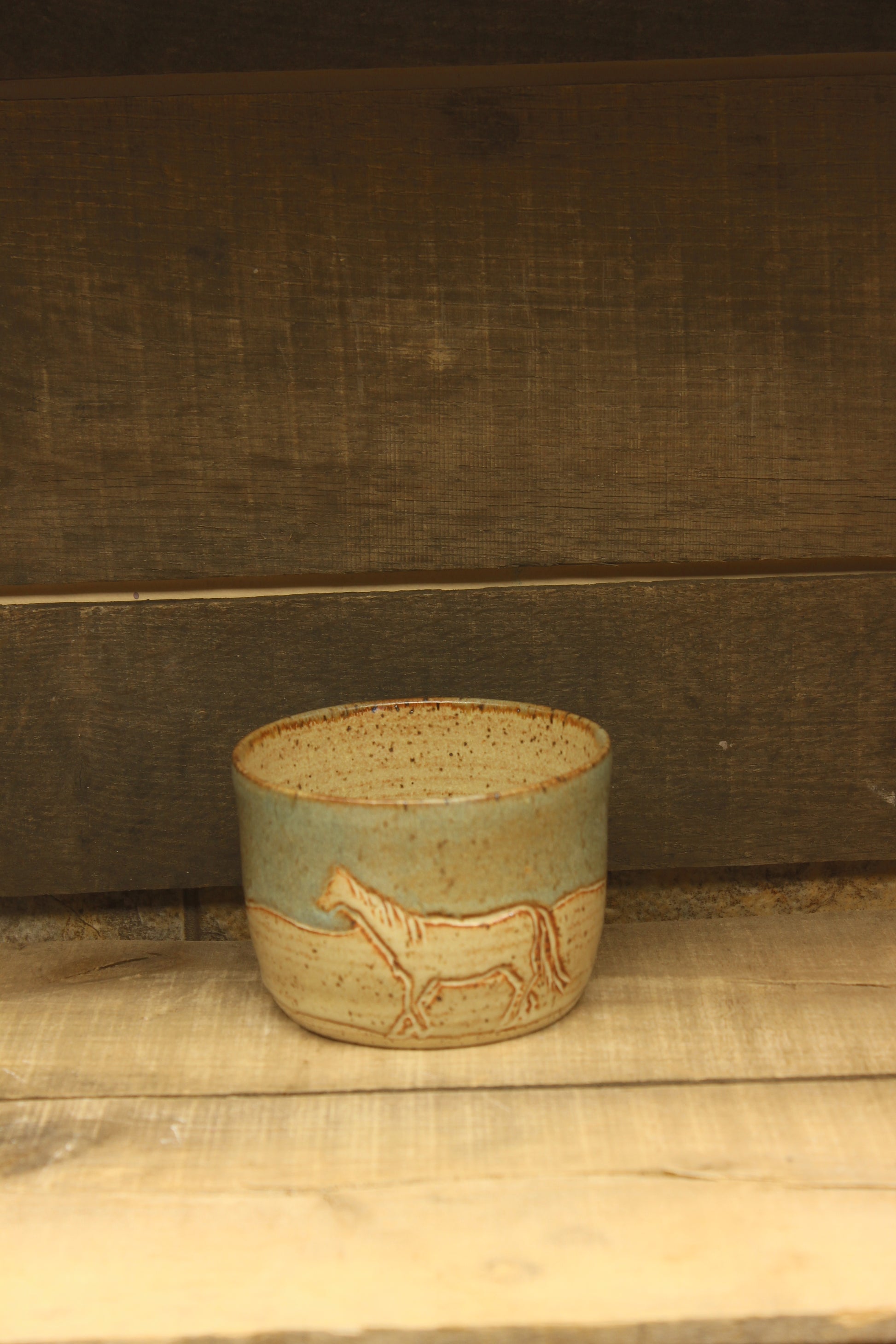 Small ceramic tan and blue bowl with carved horse and cow