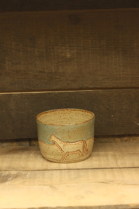 Small ceramic tan and blue bowl with carved horse and cow