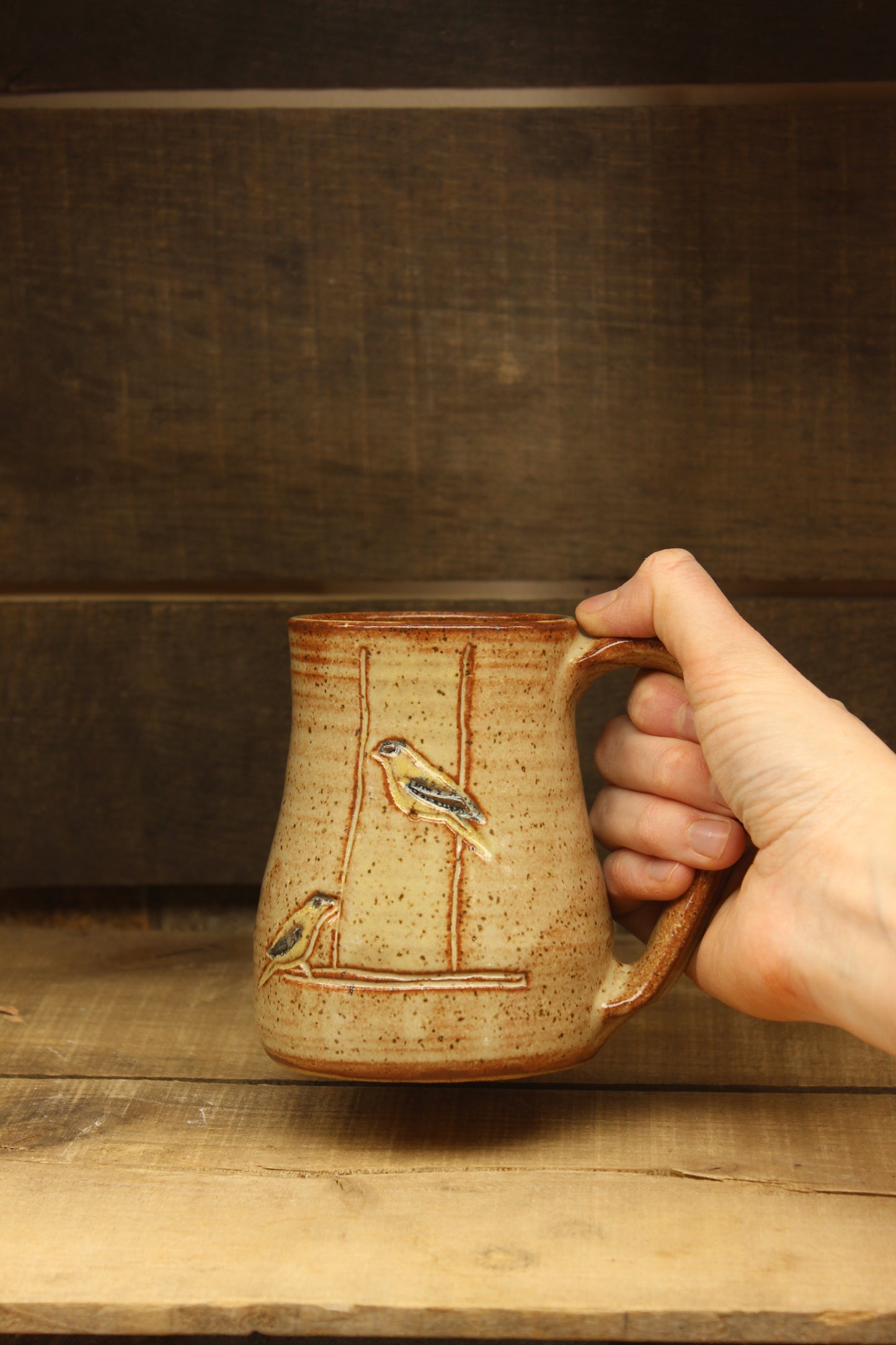 wheelthrown ceramic mug with goldfinches at feeder